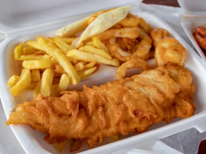 Fish and chips with onion rings in a takeaway tray